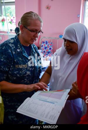 180502-N-QV906-024 TRINCOMALEE, Sri Lanka (May 2, 2018) Cmdr. Brenda Reseter, assigned to Military Sealift Command hospital ship USNS Mercy (T-AH-16), discusses a child's health and development record during a tour of Kinniya Base Hospital, May 2, 2018. Mercy is currently deployed in support of Pacific Partnership 2018 (PP18). PP18's mission is to work collectively with host and partner nations to enhance regional interoperability and disaster response capabilities, increase stability and security in the region, and foster new and enduring friendships across the Indo-Pacific Region. Pacific Pa Stock Photo