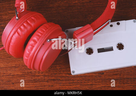 Top view of vintage headphones and audio cassette on wooden table. Retro technology concept