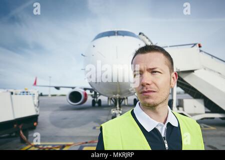 Member ground crew worker at the airport in front of the airplane. Stock Photo