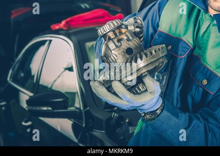 Caucasian Car Mechanic in His 30s with Part of Car Differential in Hands. Vehicle Service Theme. Stock Photo