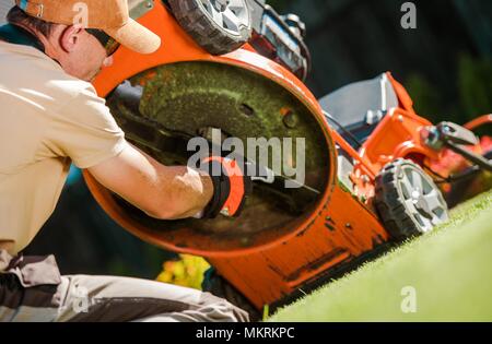 Caucasian Gardener in His 30s Checking Lawn Mower Blades. Stock Photo