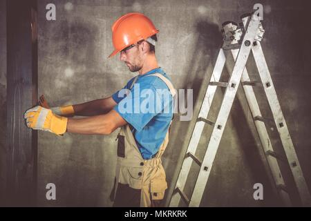 Construction Contractor Worker in His 30s Measuring Wooden Elements of the Building. Stock Photo