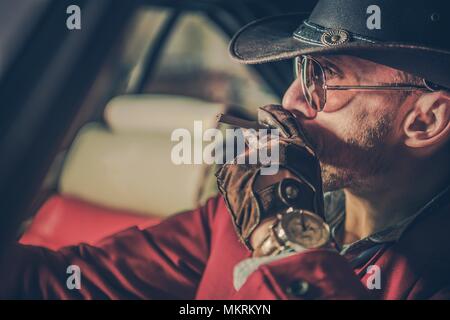 American Cowboy with Cigarette Closeup Portrait. Caucasian Men Western Wear in Leather Gloves is About to Light Up His Cigarette. Stock Photo