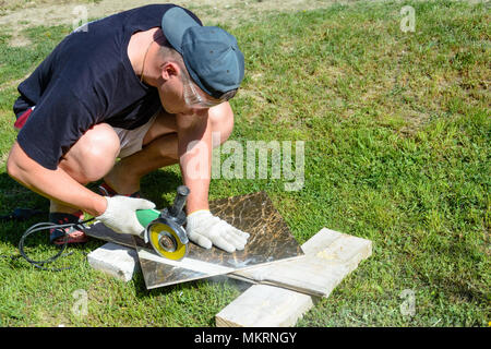 The plasterer master cuts the marble tile round the ceramic disc 2018 Stock Photo