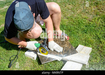 The plasterer master cuts the marble tile round the ceramic disc 2018 Stock Photo