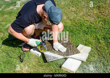 The plasterer master cuts the marble tile round the ceramic disc 2018 Stock Photo