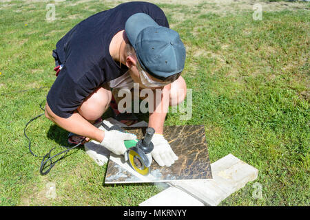 The plasterer master cuts the marble tile round the ceramic disc 2018 Stock Photo