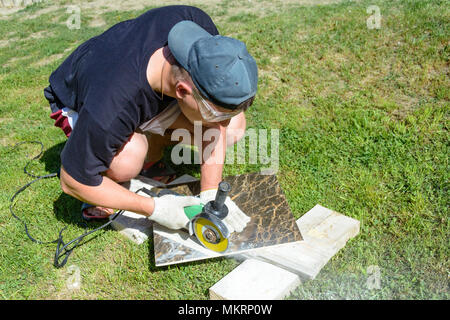 The plasterer master cuts the marble tile round the ceramic disc 2018 Stock Photo