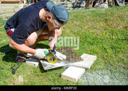 The plasterer master cuts the marble tile round the ceramic disc 2018 Stock Photo