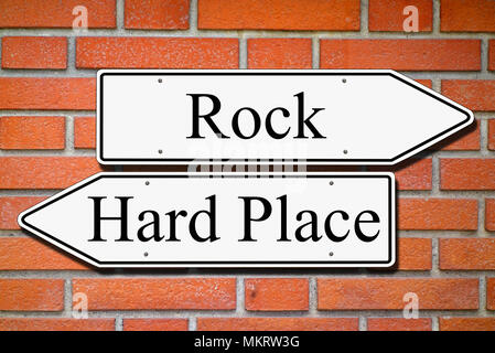 Between rock and hard place signpost concept bricks wall Stock Photo