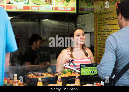 Smilling lady vendor sells fast food at the Mexican street stall in Camden Stables & Lock Market, Camden Town, London, England, UK. Stock Photo