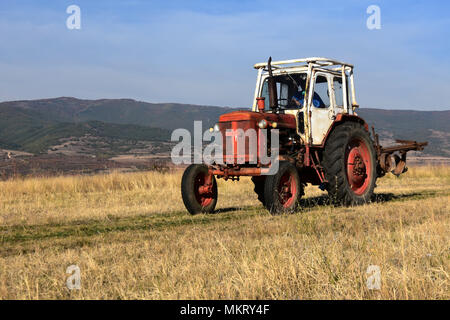 Saparava Banya, Bulgaria - October 15, 2017: Autumn plowing. Old tractor getting back from work on the field at the end of the day Stock Photo