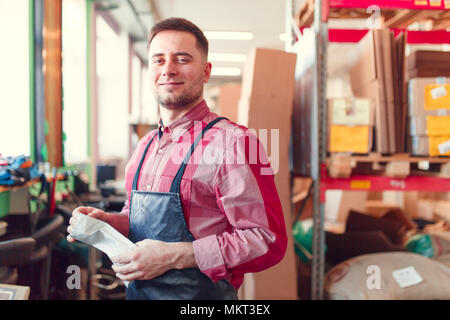 Picture of man in apron with bag in hands at shop for making coffee on background Stock Photo
