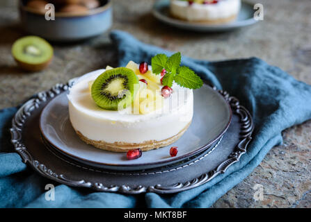 Delicious unbaked mini cheesecakes topped with pineapple, kiwi and pomegranate Stock Photo