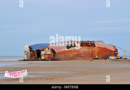 Blue grey sky view across low tide sand beach to Riverdance Ferry on its side and being dismantled with aerial platforms, Anchorsholme, Cleveleys, UK Stock Photo