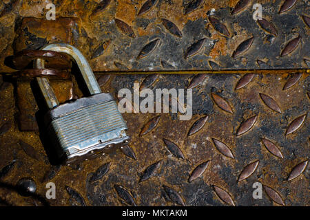 A silver lock on a metal street grate Stock Photo