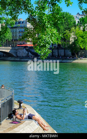 A young french man reading a book, seine river, paris, france Stock Photo