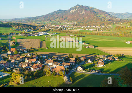 Aerial view of a beautiful landscape with traditional houses, green meadows, hills and cows near the Gruyeres, Switzerland Stock Photo