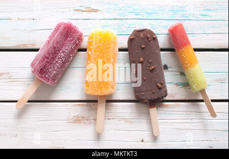 Various flavored ice popsicles over wooden background Stock Photo