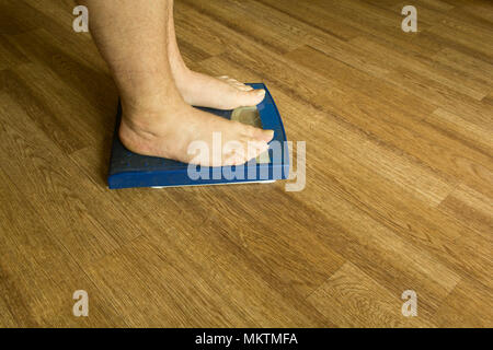 Men's legs stand on a mechanical scales of blue color Stock Photo