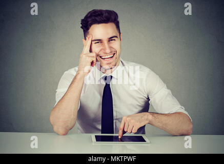 Successful young business man with tablet sitting at desk smiling looking at camera Stock Photo