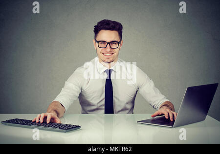 Cheerful executive office worker sitting at table with computer smiling at camera. Stock Photo