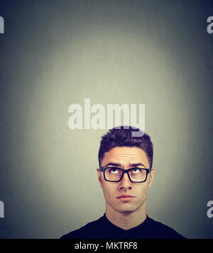 Doubtful man in glasses looking up Stock Photo