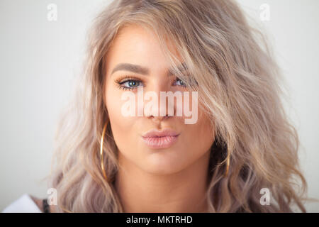 Beautiful woman puckering lips with eyes open over white background Stock Photo