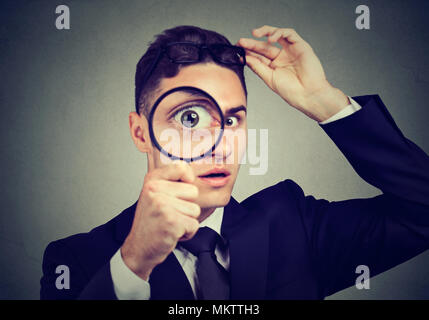 Curious man taking off glasses looking through a magnifying glass Stock Photo