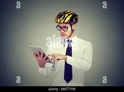 Young cautious man in helmet browsing tablet carrying out business safely. Stock Photo