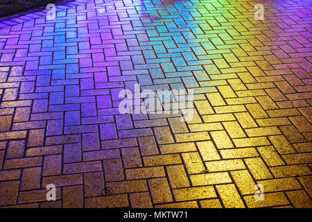 city road paved with tiles in the light of colored lanterns on the night Stock Photo