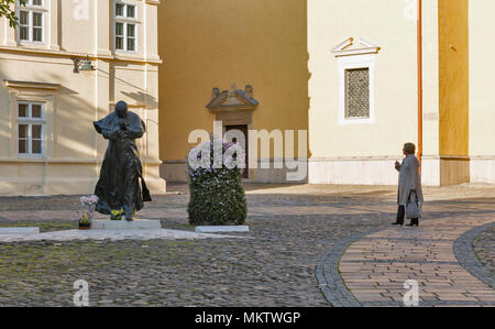 PRESOV, SLOVAKIA - OCTOBER 01, 2017: Senior woman looks at Statue of Pope John Paul II close to St. Nicholas church in Old Town. It is a city in Easte Stock Photo