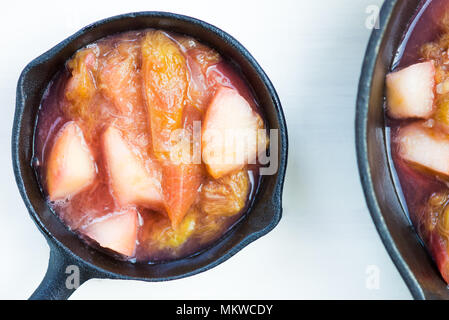 Homemade rhubarb and apple compote for making crumble in the cast iron pans Stock Photo