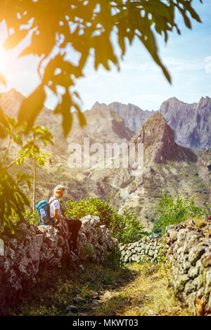 Girl resting on the hiking trail leading through arid rocky terrain towards Coculli village on Santo Antao Cape Verde Stock Photo