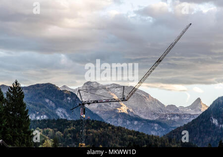 Construction tower crane against a cloudy mountain landscape in Bavaria, Grermany Stock Photo