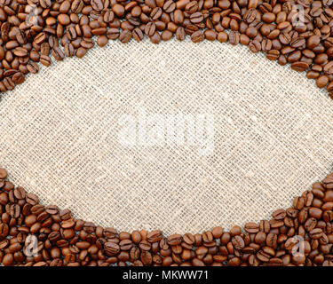 Colorful brown roasted coffee beans placed on natural sacking as oval frame for your text Stock Photo
