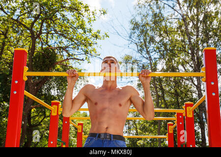 young man doing gymnastic exercises in the yard on sunny summer day Stock Photo