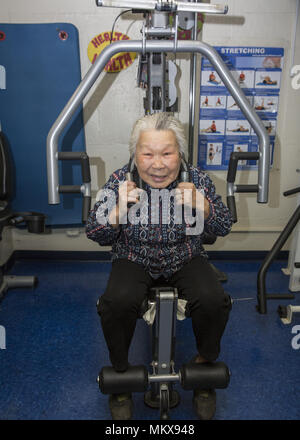 91 year old Chinese woman keeps fit on the exercise machines at a senior center on the Lower East Side, Manhattan, New York City. Stock Photo