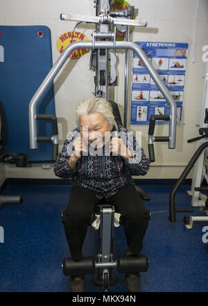 91 year old Chinese woman keeps fit on the exercise machines at a senior center on the Lower East Side, Manhattan, New York City. Stock Photo
