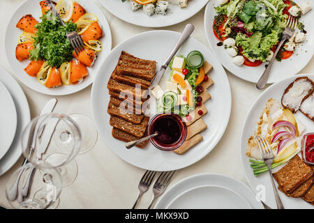 Served dishes to the table for holiday. Cutlery and food on white tablecloths in the restaurant. Design a festive Banquet. Luxurious food for guests and visitors. Stock Photo
