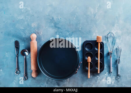 Baking forms and muffin tin with whisks, spoons, flour, sugar and spices on a marble kitchen table. Baking tools and ingredients with copy space. Making pastry concept. Stock Photo