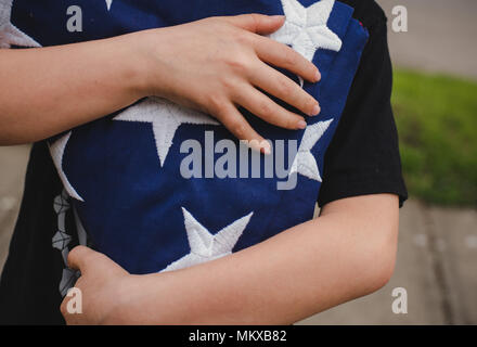 A young boy holding a folded American flag. Stock Photo