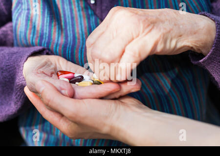 Close up picture of elderly disabled woman's hands receiving medical drugs from caregiver Stock Photo
