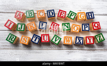 Multi-colored wooden letter blocks making the alphabet on white wood background Stock Photo
