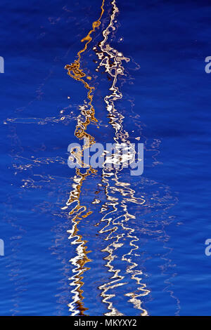 Ripples and reflections of yacht masts on sky-blue water in Scarborough harbour. Stock Photo