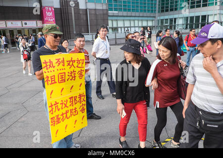 Mainland Chinese tour groups at the base of Taipei 101 Tower,attract two demonstrations,Taipei,Taiwan,Asia.The mainland Chinese tour buses park infront of Taipei 101 Tower,the second tallest building in the world,for the mainland Chinese to access this tourist attraction. On disembarking and getting on the buses nationalist Chinese supporters welcome them flying the Chinese flag.The pro-China supporters are there as a counter-demonstration to another group of demonstrators,the Falun Dafa/Falun Gong that have placards protesting about the persecution of members of the banned organization within Stock Photo