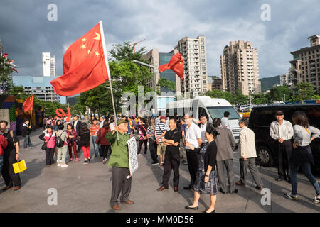 Mainland Chinese tour groups at the base of Taipei 101 Tower,attract two demonstrations,Taipei,Taiwan,Asia.The mainland Chinese tour buses park infront of Taipei 101 Tower,the second tallest building in the world,for the mainland Chinese to access this tourist attraction. On disembarking and getting on the buses nationalist Chinese supporters welcome them flying the Chinese flag.The pro-China supporters are there as a counter-demonstration to another group of demonstrators,the Falun Dafa/Falun Gong that have placards protesting about the persecution of members of the banned organization within Stock Photo
