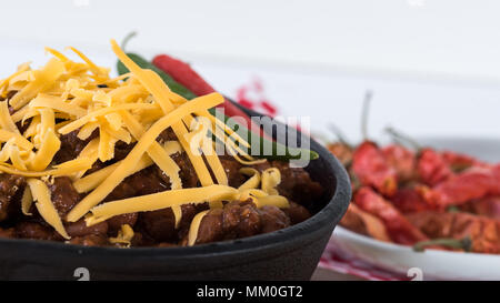 Cast Iron skillet full of spicy beef and bean chili with cheddar cheese, on white background with copy space for text Stock Photo