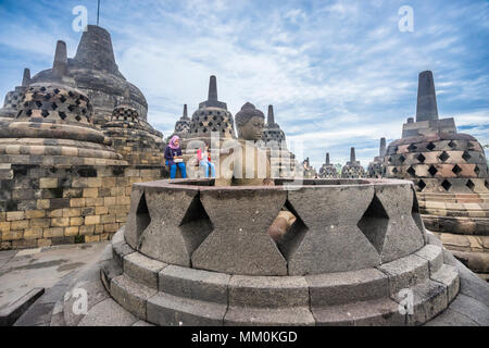 an exposed Buddha statue in an opened perforated stupa on the circular top terrace of 9th century Borobudur Buddhist temple gazes serenly over the Ked Stock Photo