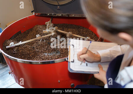 lady with clipboard checking coffee beans in vat Stock Photo